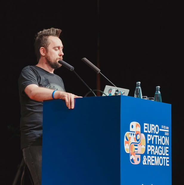 A person speaking at a podium with a laptop and microphone