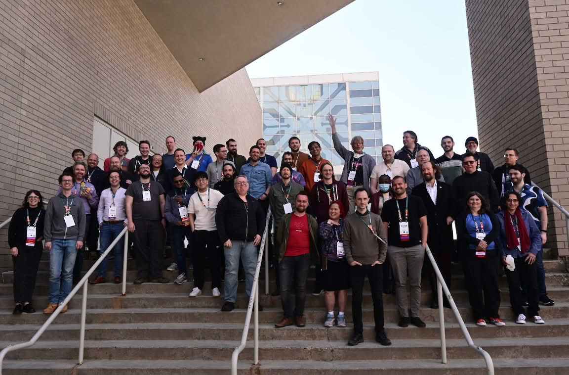 Group of people standing on stairs outside a building, posing for a group photo