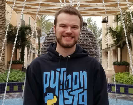 A person smiling and wearing a Python t-shirt