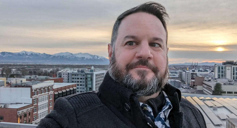 A person standing on a rooftop with a city and mountains in the background