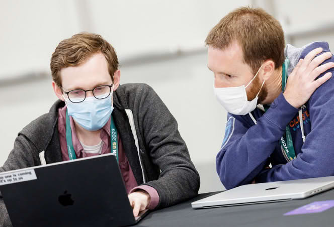 Two people discussing something on a laptop