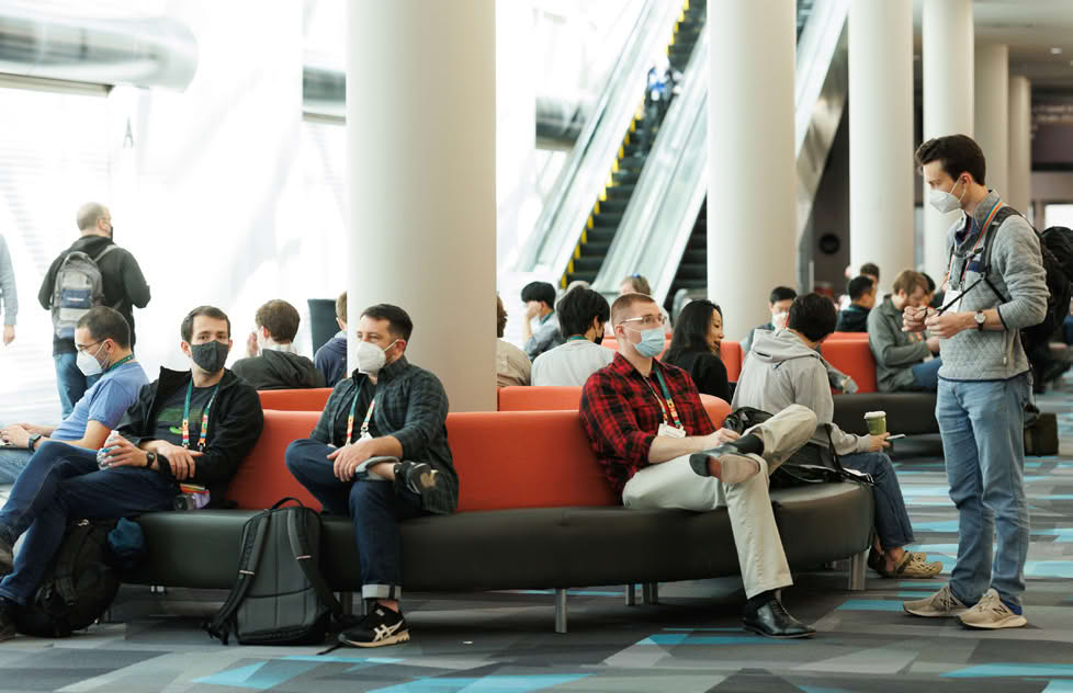 People sitting on a red couch in a conference hall