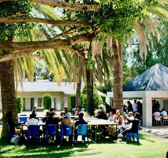 Group of people sitting outside under palm trees