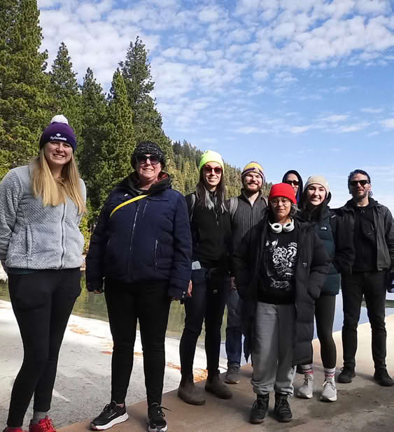 Group of staff members standing together outdoors with trees in the background