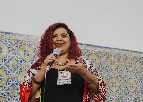 A person speaking at a Python event, holding a microphone and wearing a badge that says 'Afro Python'