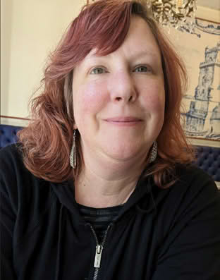 Portrait of a person with shoulder-length hair, smiling at the camera