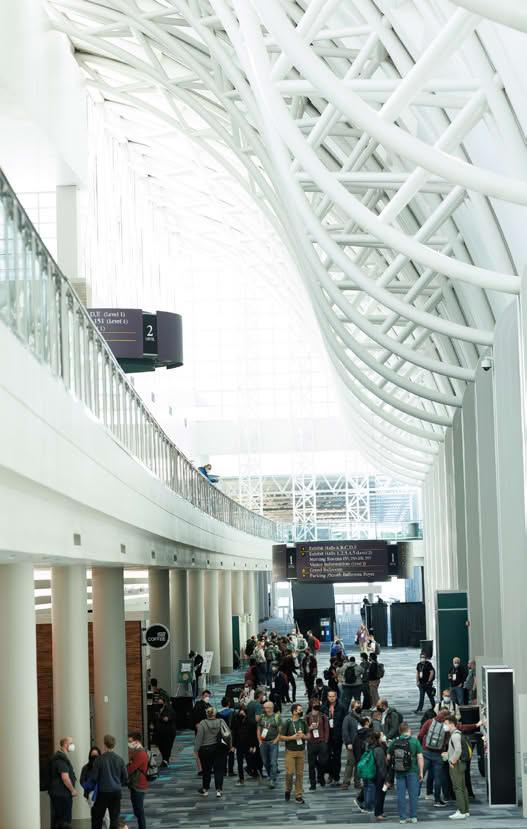 A large hallway with people walking and a high ceiling with white structural beams